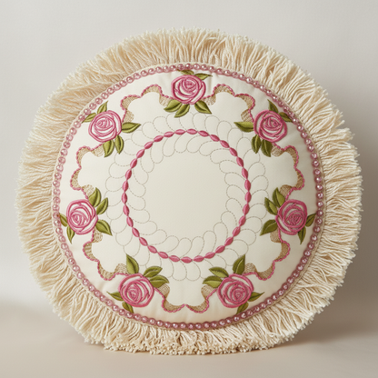 Round embroidered cushion with pink roses and white fringes on a light background